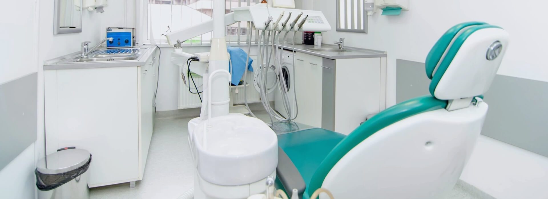 A dentist 's office with a sink and dental equipment.