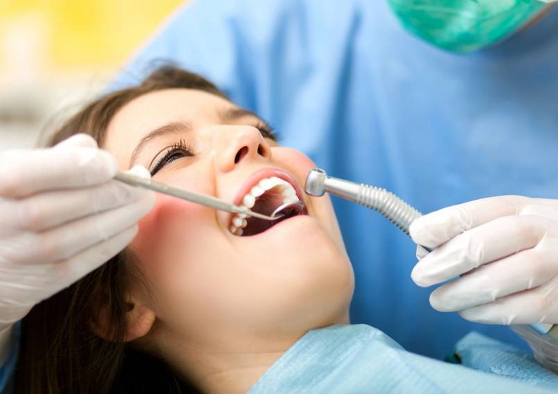 A woman is getting her teeth cleaned by dentist.