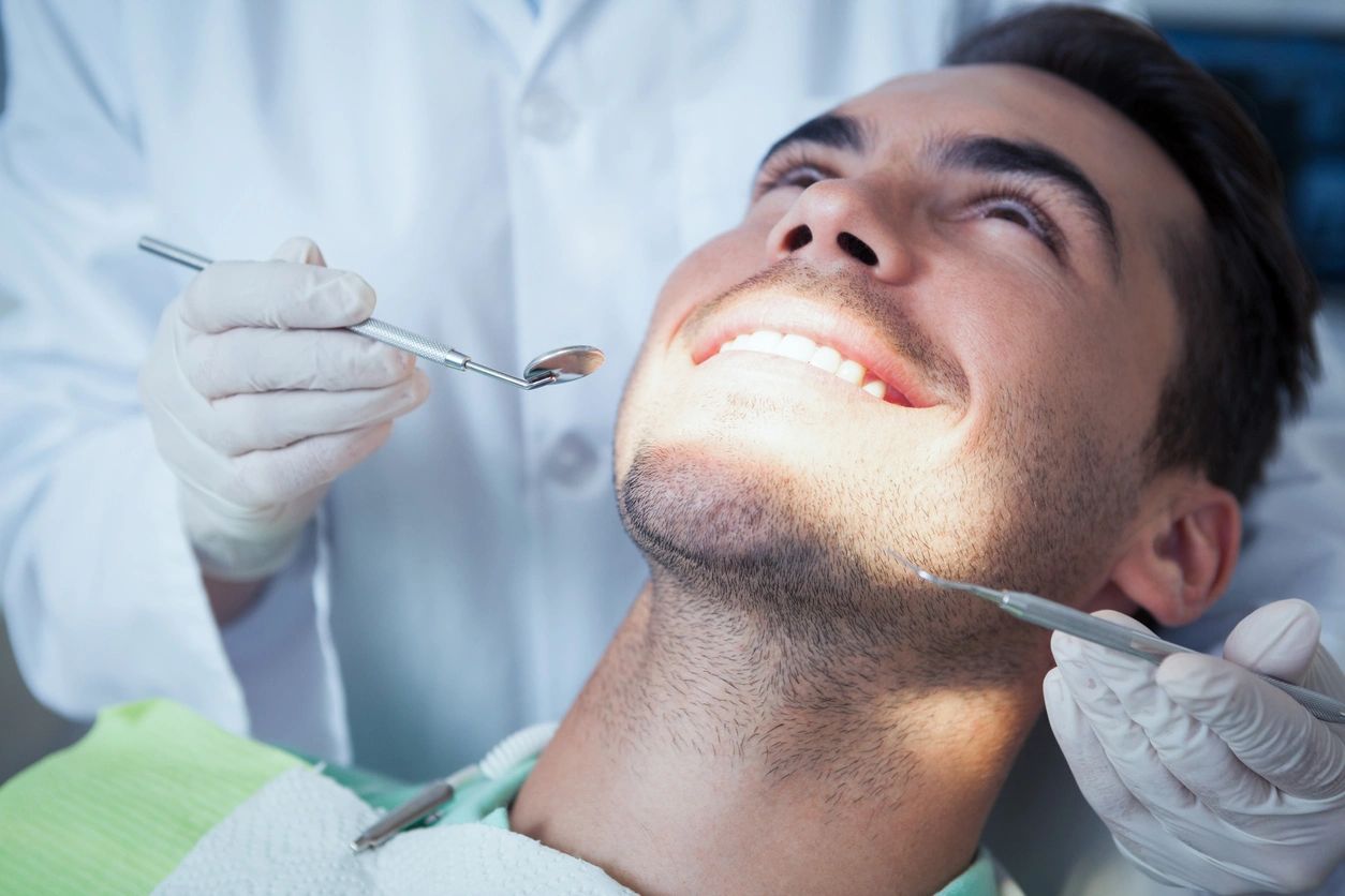 A man is getting his teeth checked by an dentist.